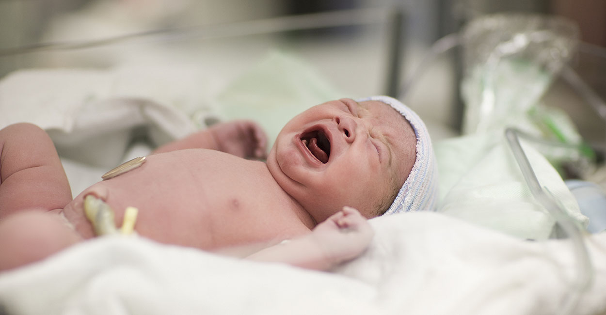Newborn baby girl crying in hospital bassinet